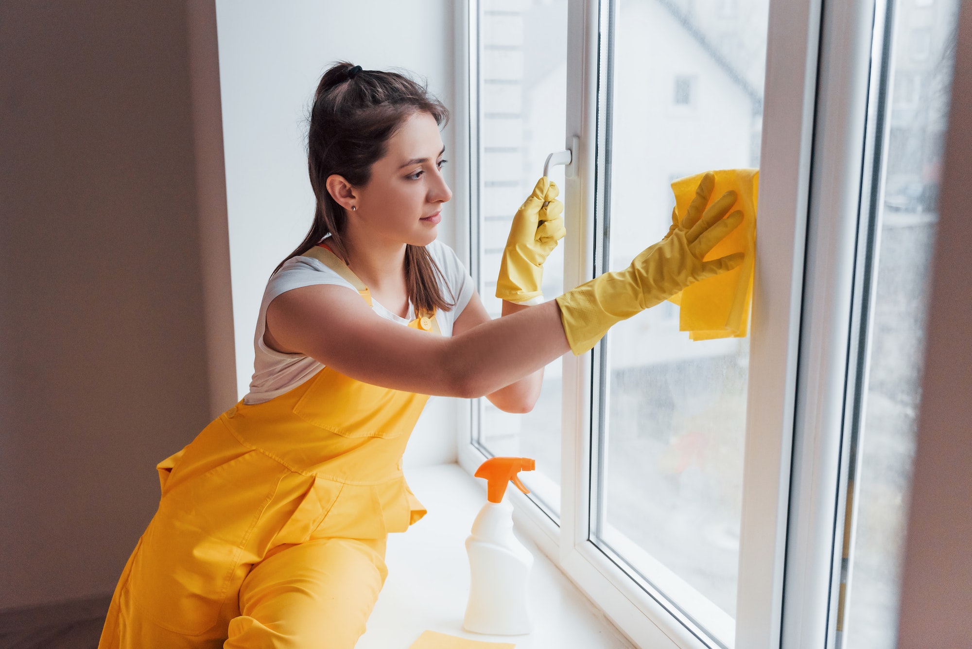 Housewife in yellow uniform cleaning windows. House renovation conception